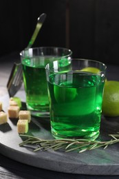 Photo of Absinthe in glasses, rosemary, brown sugar and lime on table. Alcoholic drink