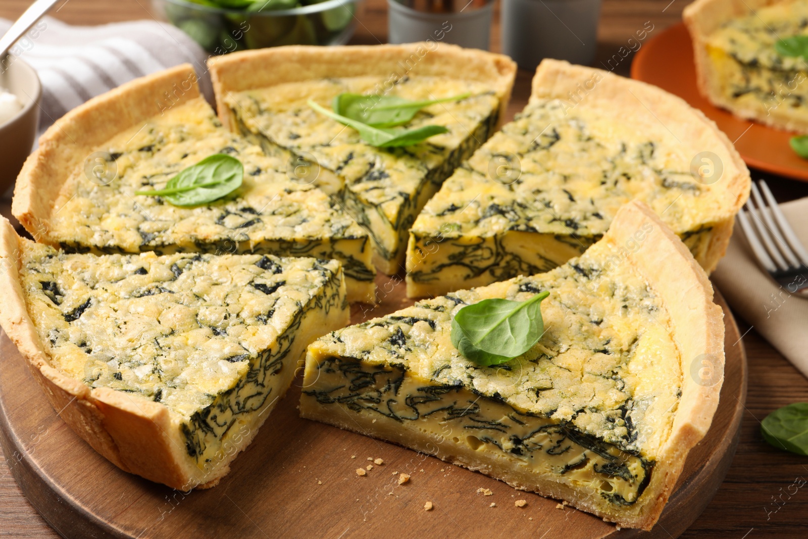 Photo of Cut delicious spinach pie on wooden board, closeup