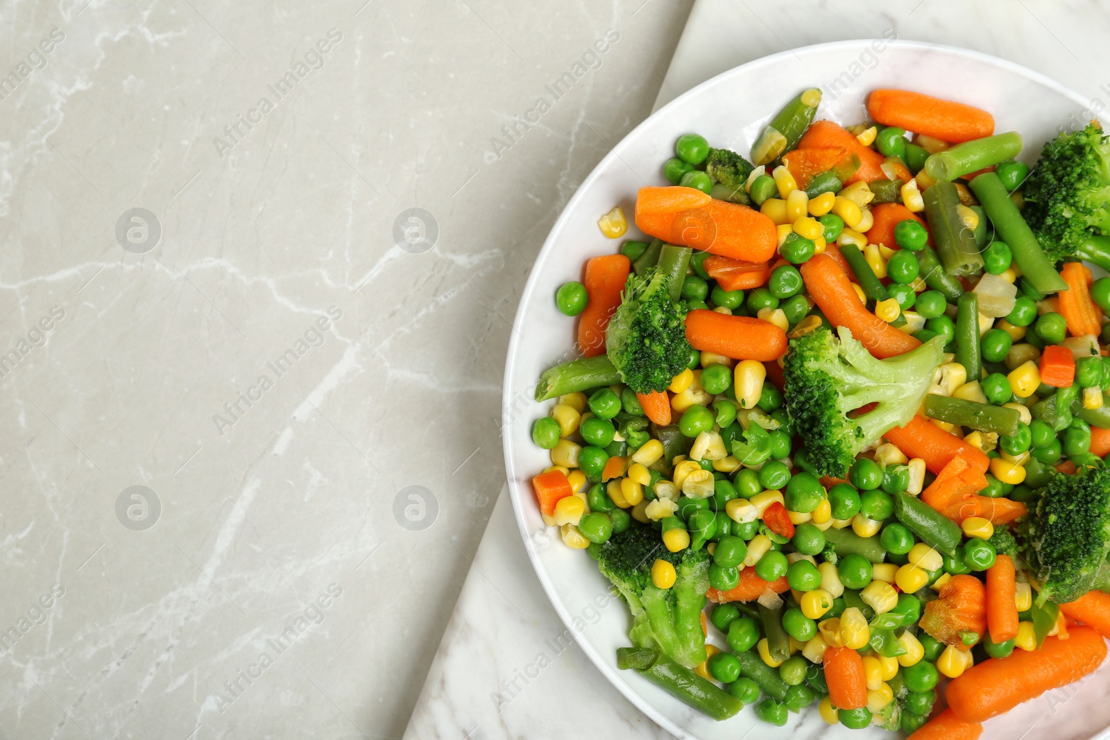 Photo of Plate with mix of frozen vegetables on light background, top view