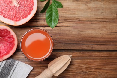 Photo of Tasty freshly made grapefruit juice and fruit on wooden table., flat lay. Space for text