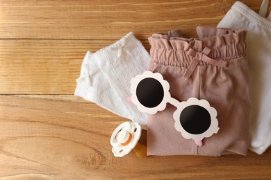 Photo of Stylish child clothes and accessories on wooden background, flat lay