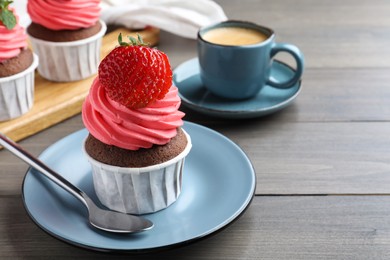 Photo of Sweet cupcake with fresh strawberry served on wooden table. Space for text