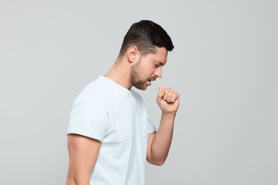 Photo of Man coughing on light gray background. Sore throat