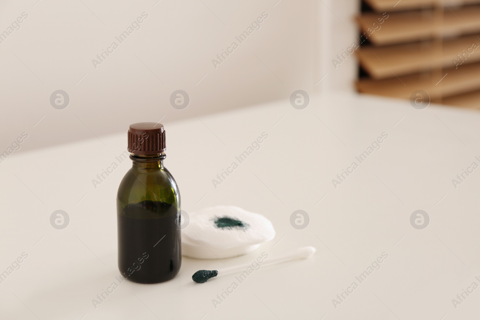 Photo of Bottle of brilliant green, cotton bud and pads on white table indoors