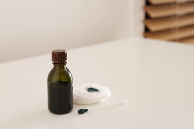 Bottle of brilliant green, cotton bud and pads on white table indoors