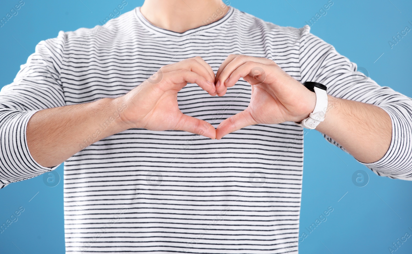 Photo of Man making heart with his hands on color background, closeup