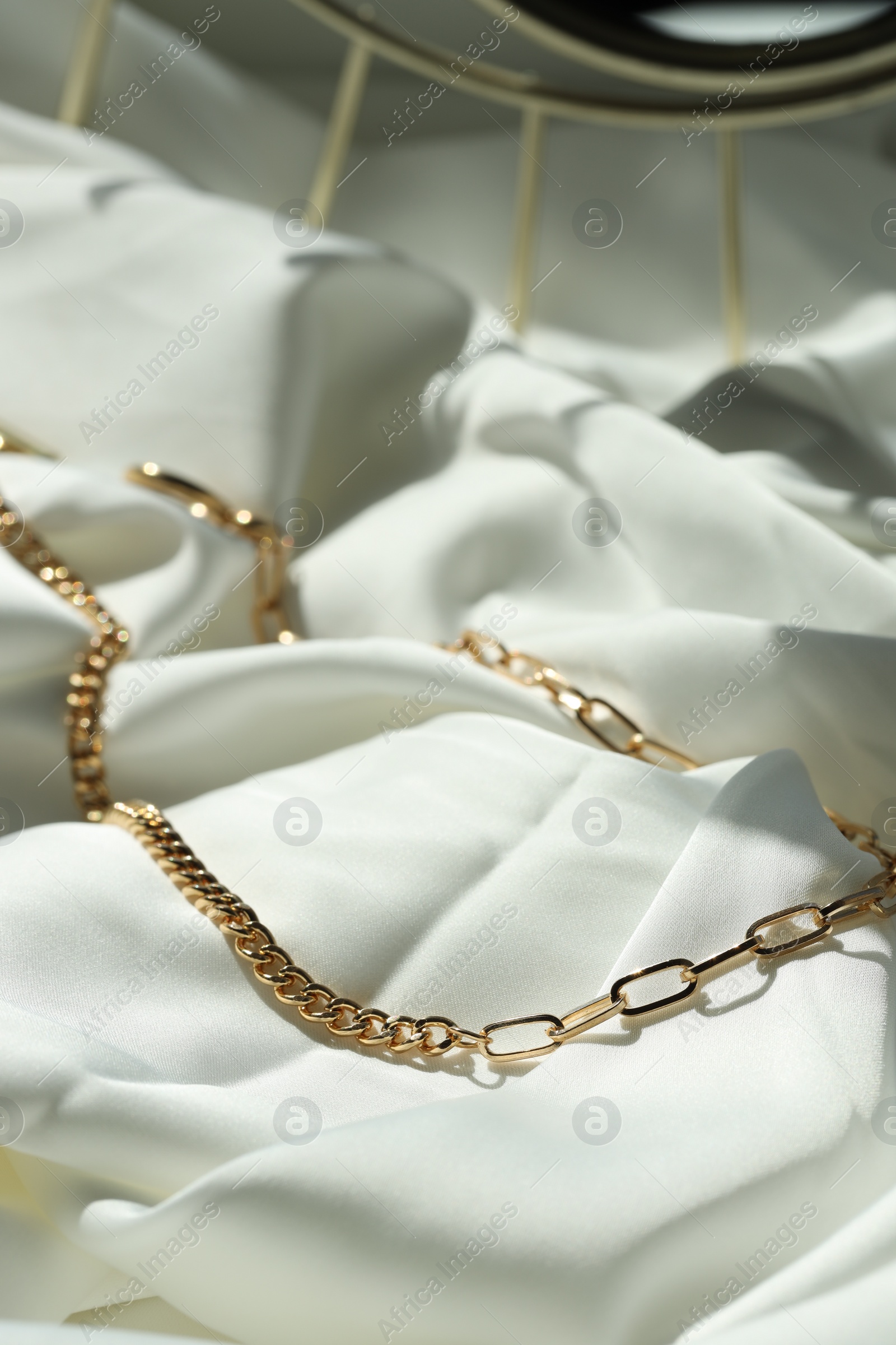 Photo of Metal chain on white fabric. Luxury jewelry