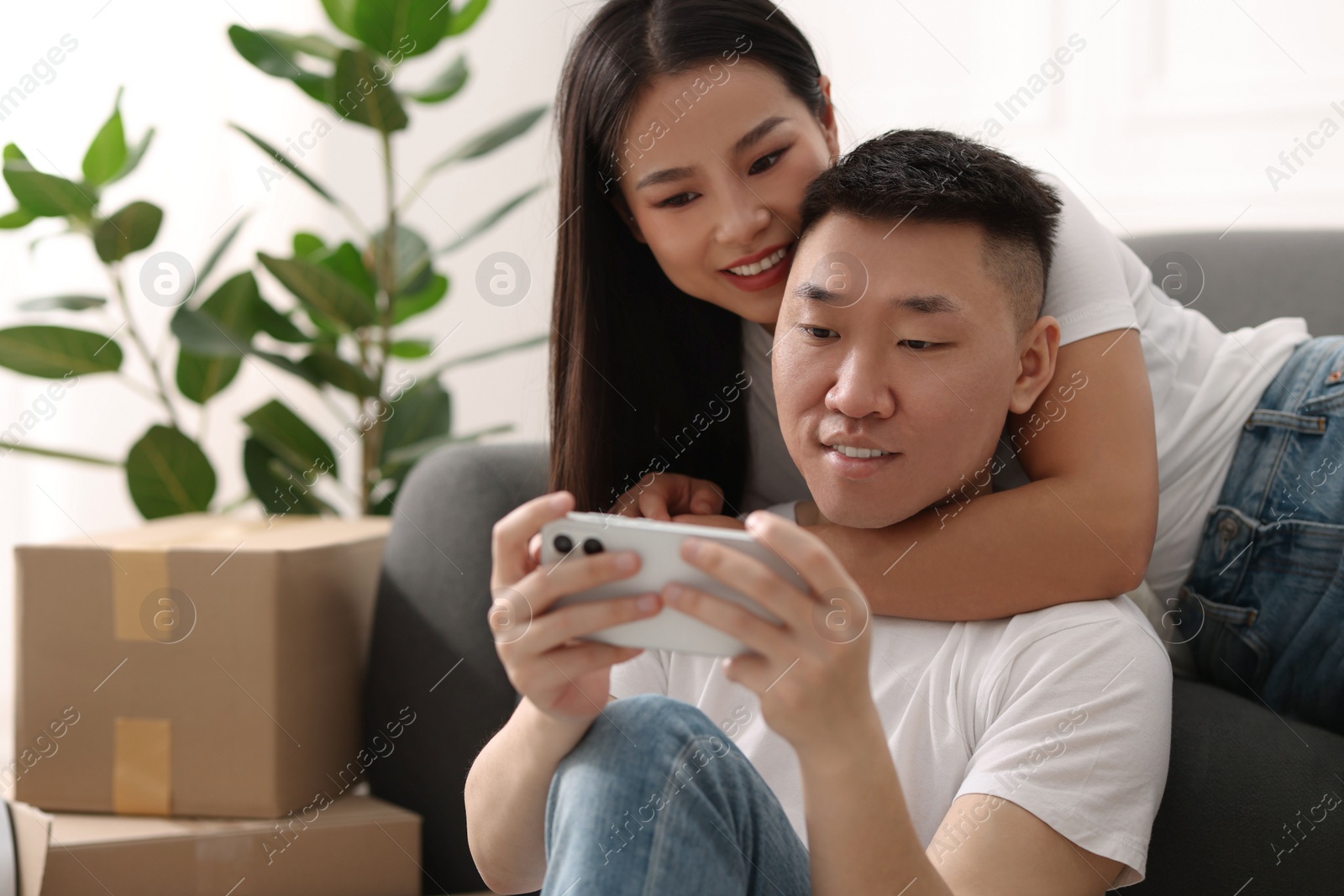 Photo of Happy couple with smartphone in their new apartment