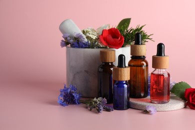 Photo of Aromatherapy. Different essential oils, flowers, mortar and pestle on pink background, space for text