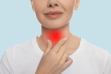 Endocrine system. Woman doing thyroid self examination on light blue background, closeup