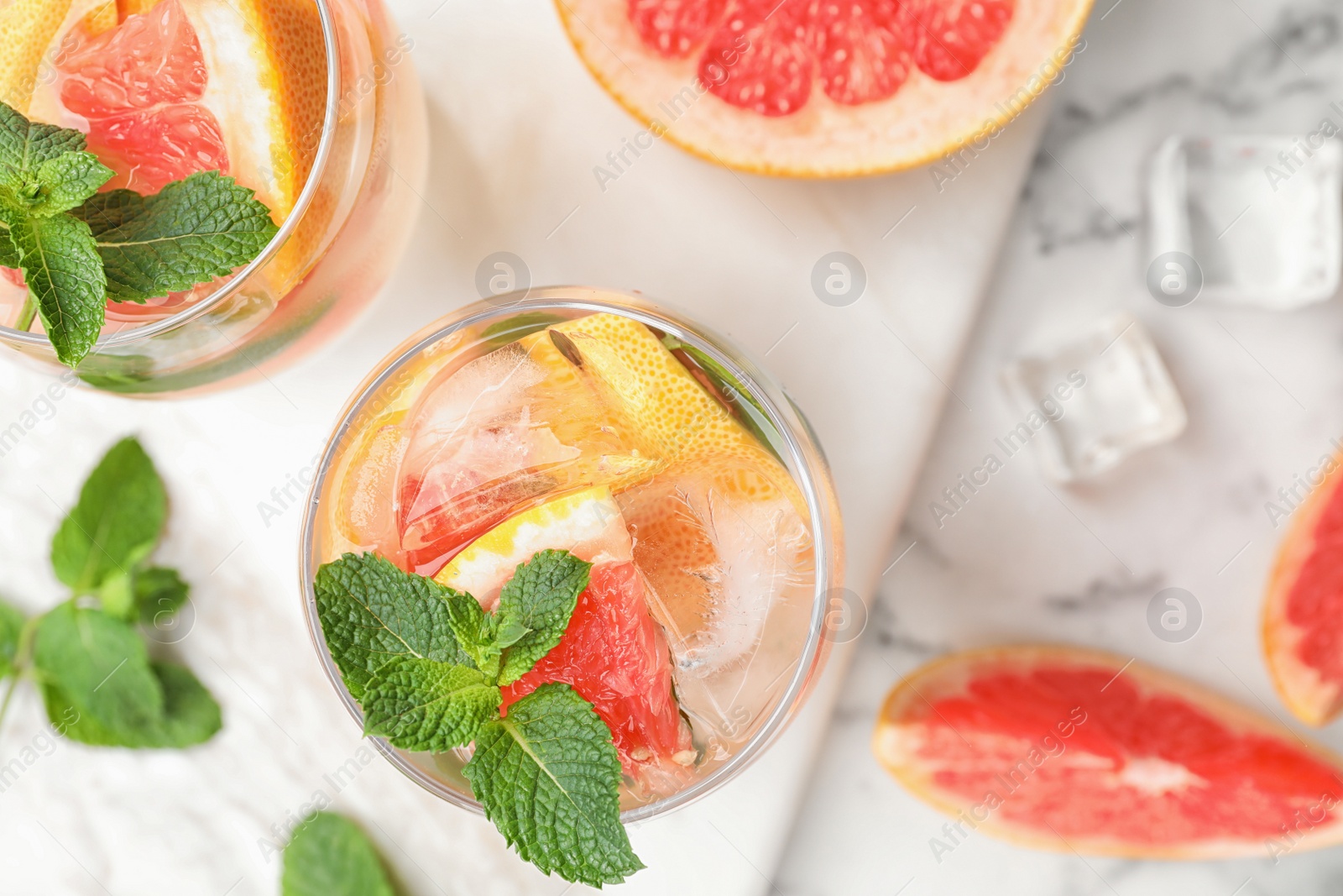 Photo of Glasses of refreshing drink with grapefruit and mint on marble table, top view. Space for text