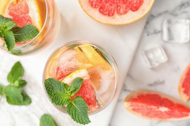 Glasses of refreshing drink with grapefruit and mint on marble table, top view. Space for text