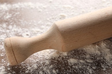 Photo of Rolling pin and scattered flour on table, closeup