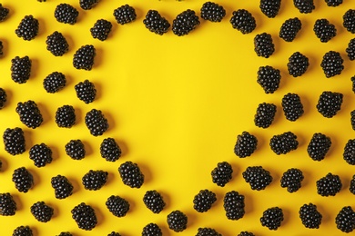 Flat lay composition with ripe blackberries on yellow background. Space for text