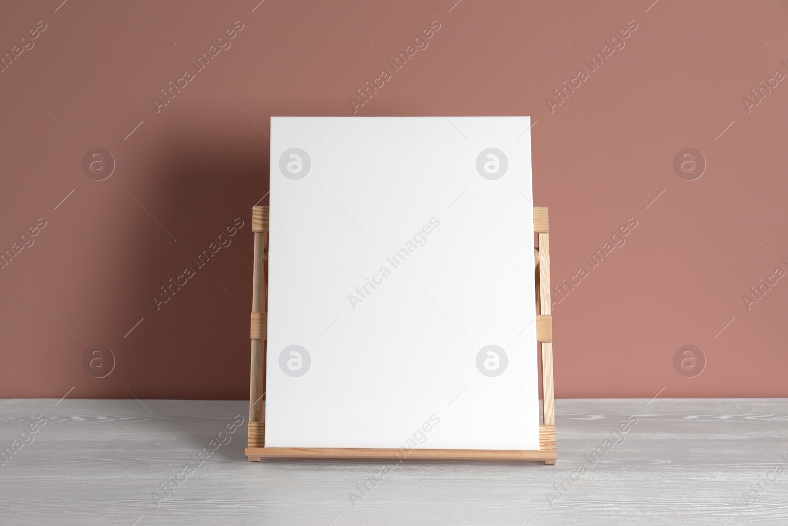 Photo of Wooden easel with blank canvas on white table