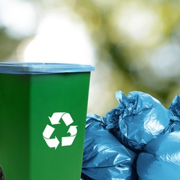 Image of Plastic bags full of garbage and waste bin on blurred background, space for text