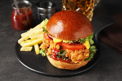 Photo of Delicious burger with crispy chicken patty and french fries on black table
