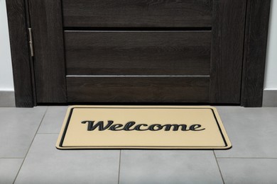 Photo of Beautiful beige doormat with word Welcome on floor near entrance