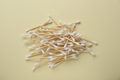 Heap of wooden cotton buds on beige background, flat lay