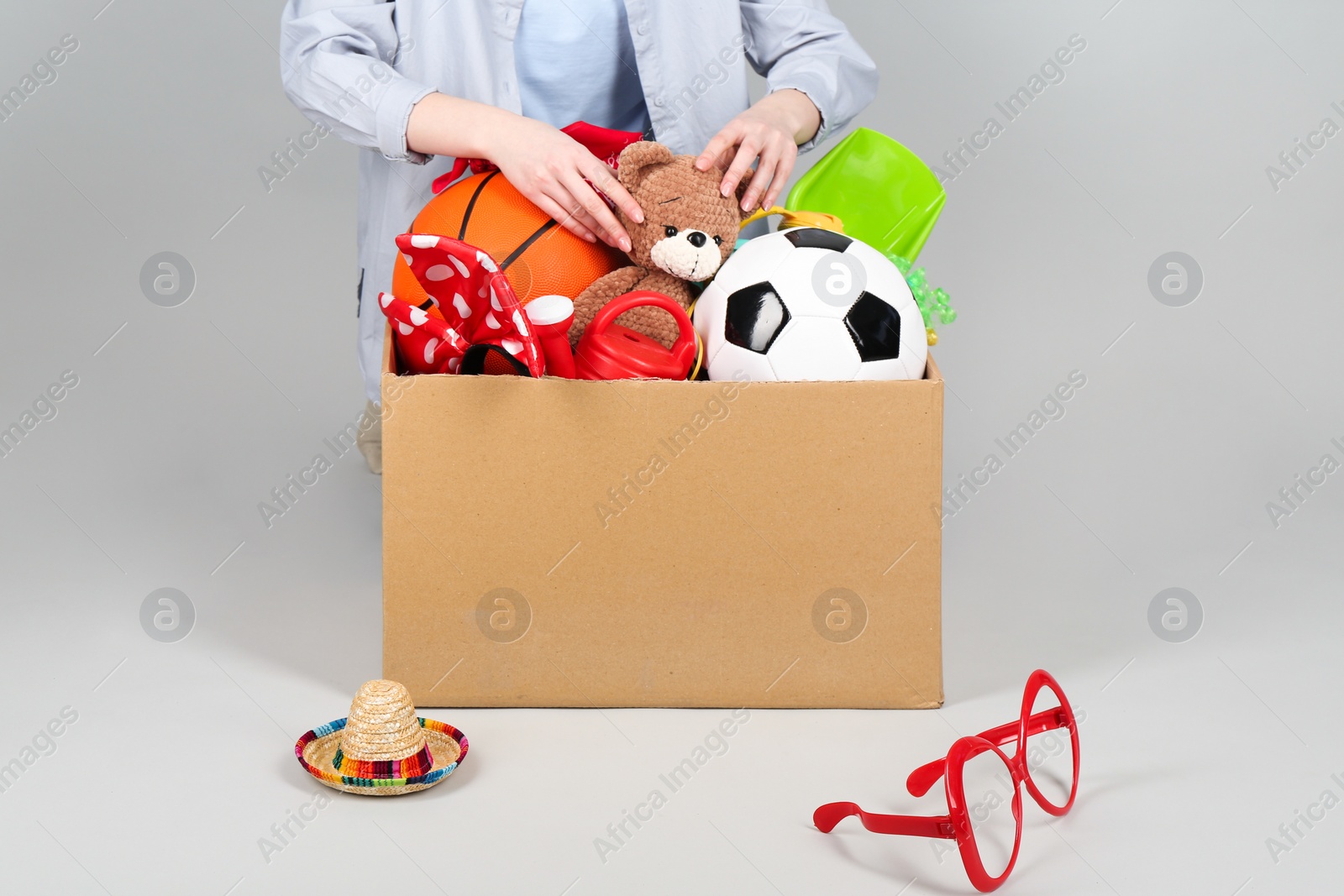 Photo of Woman with box of unwanted stuff on grey background, closeup