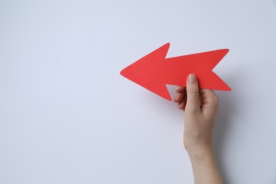 Photo of Woman holding red paper arrow on white background, top view. Space for text