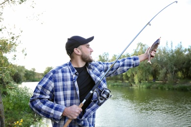 Photo of Man with rod fishing at riverside. Recreational activity