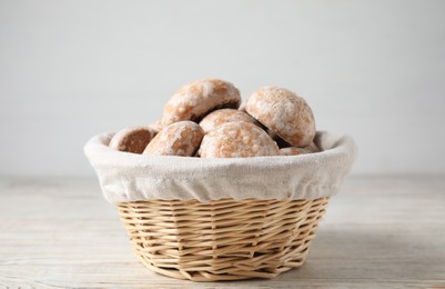 Photo of Tasty homemade gingerbread cookies in basket on white wooden table