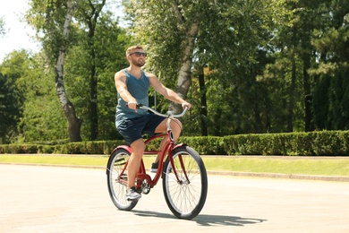 Photo of Attractive man riding bike outdoors on sunny day