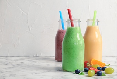 Photo of Bottles with healthy detox smoothies and ingredients on table