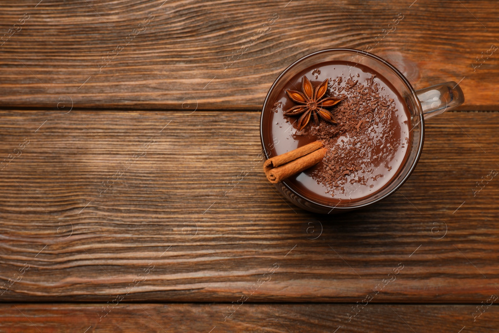 Photo of Cup of delicious hot chocolate with cinnamon stick and anise on wooden table, top view. Space for text