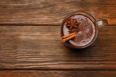 Photo of Cup of delicious hot chocolate with cinnamon stick and anise on wooden table, top view. Space for text