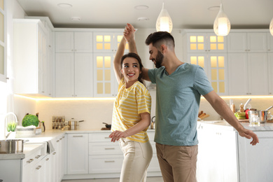 Lovely young couple dancing in kitchen. Cooking together