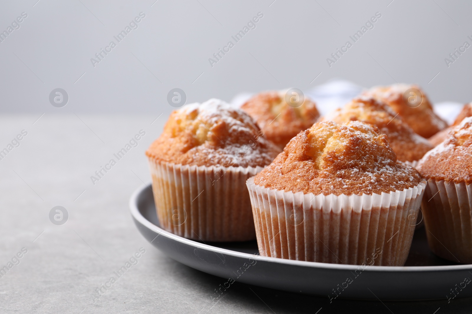 Photo of Delicious sweet muffins on light grey textured table, closeup. Space for text