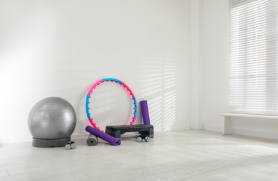 Photo of Different sports equipment near white wall in gym. Space for text