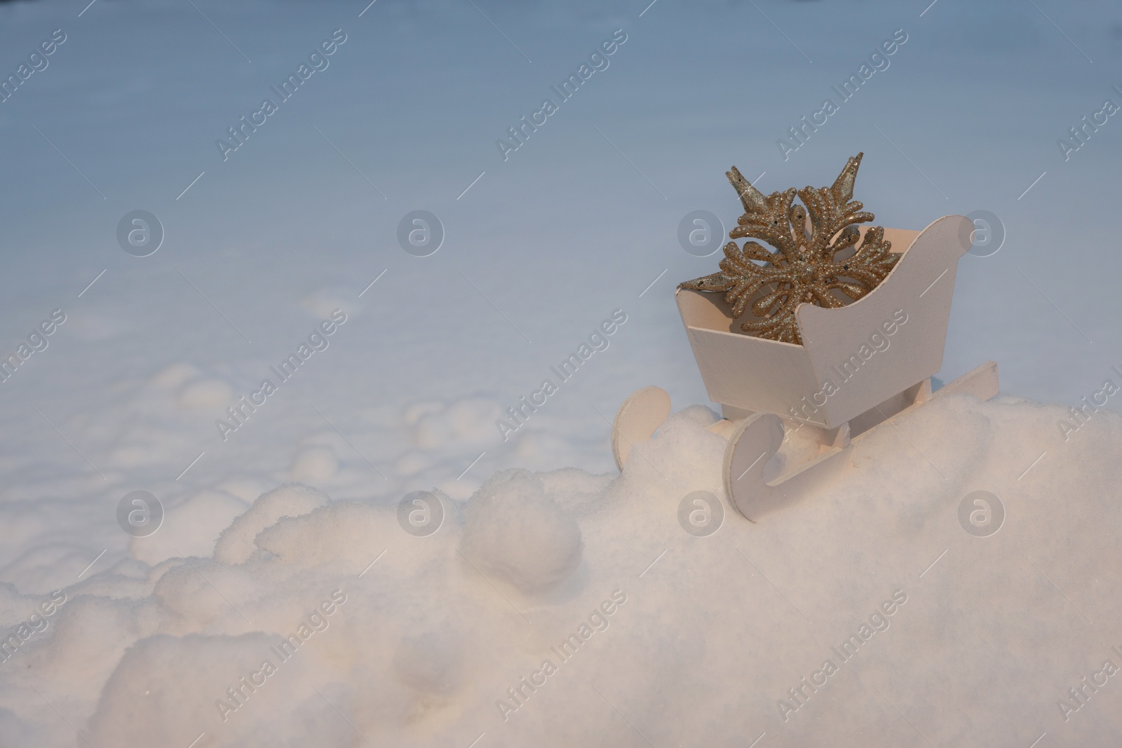 Photo of White wooden sleigh with decorative snowflake outdoors. Space for text