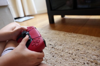 Photo of Child playing video games with controller at home, closeup. Space for text