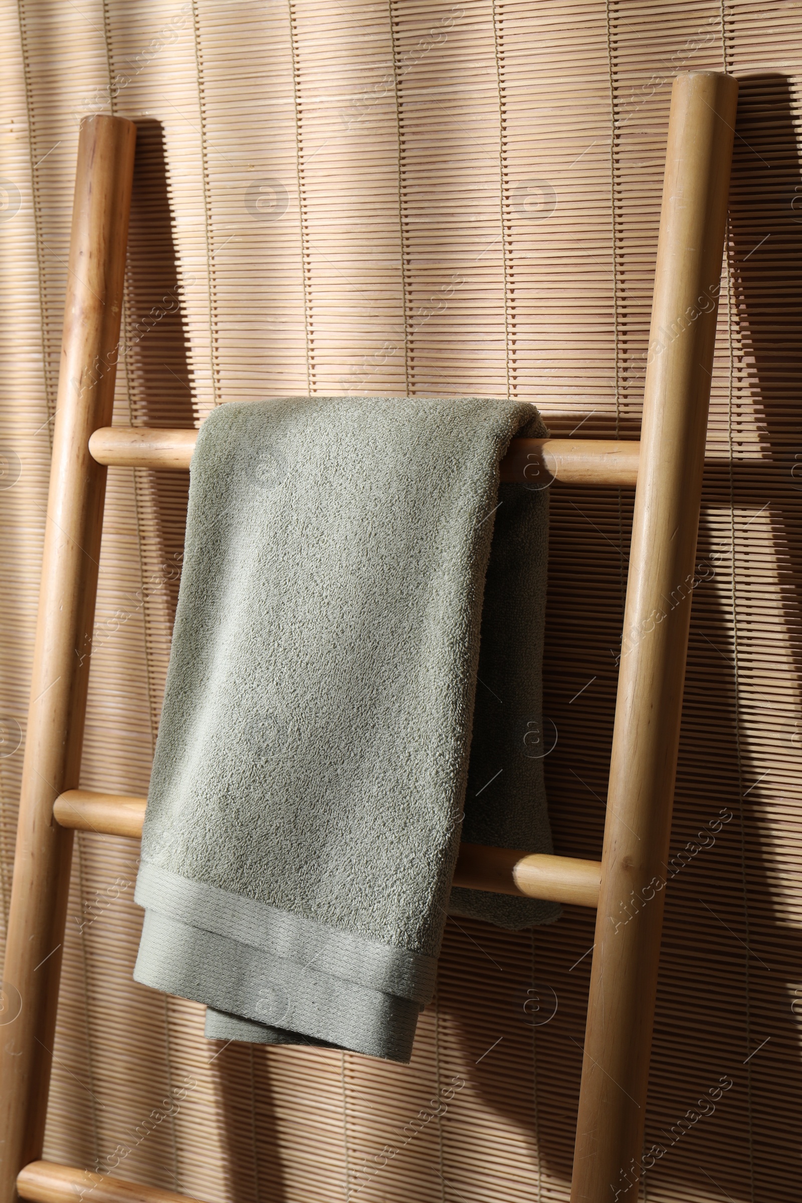 Photo of Green terry towel on wooden ladder indoors