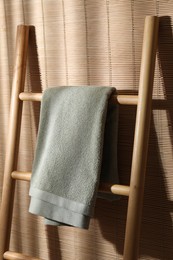 Green terry towel on wooden ladder indoors