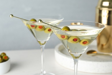 Glasses of Classic Dry Martini with olives on table against grey background