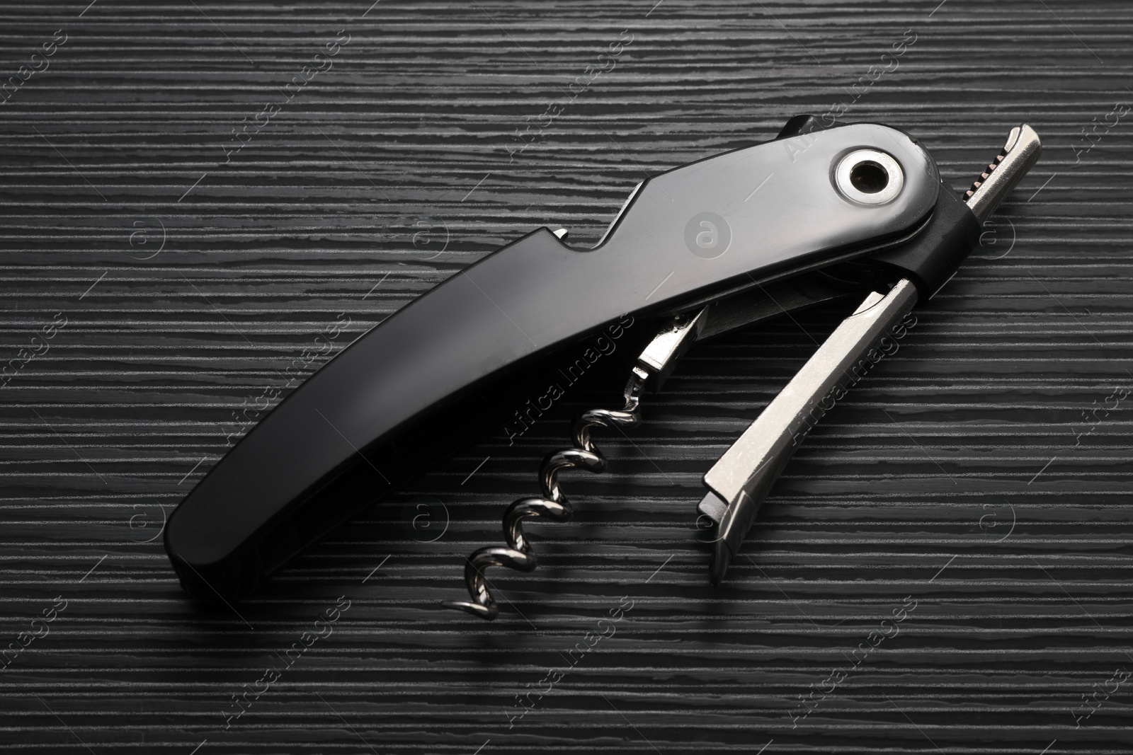 Photo of One corkscrew (sommelier knife) on black wooden table, top view