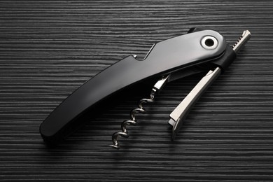 One corkscrew (sommelier knife) on black wooden table, top view