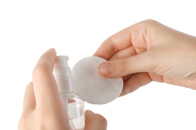 Photo of Woman pouring micellar water from bottle on cotton pad against white background, closeup