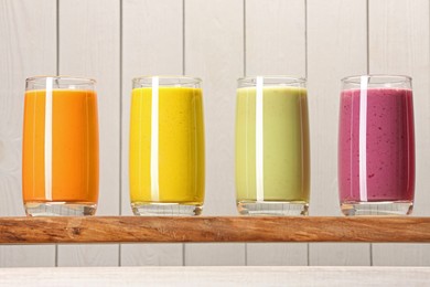 Board with many different tasty smoothies against white wooden background, closeup