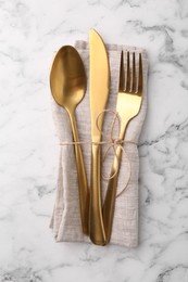 Set of stylish cutlery and napkin on white marble table, top view