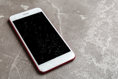 Modern smartphone with broken display on table, space for text. Device repair service