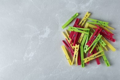 Photo of Colorful plastic clothespins on grey table, flat lay. Space for text