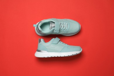 Photo of Pair of comfortable sports shoes on red background, flat lay