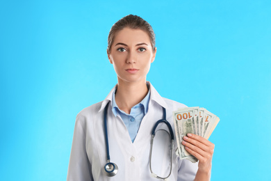 Photo of Doctor with bribe money on light blue background. Corruption in medicine
