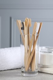Bamboo toothbrushes, towel and jar of baking soda on light grey table, closeup