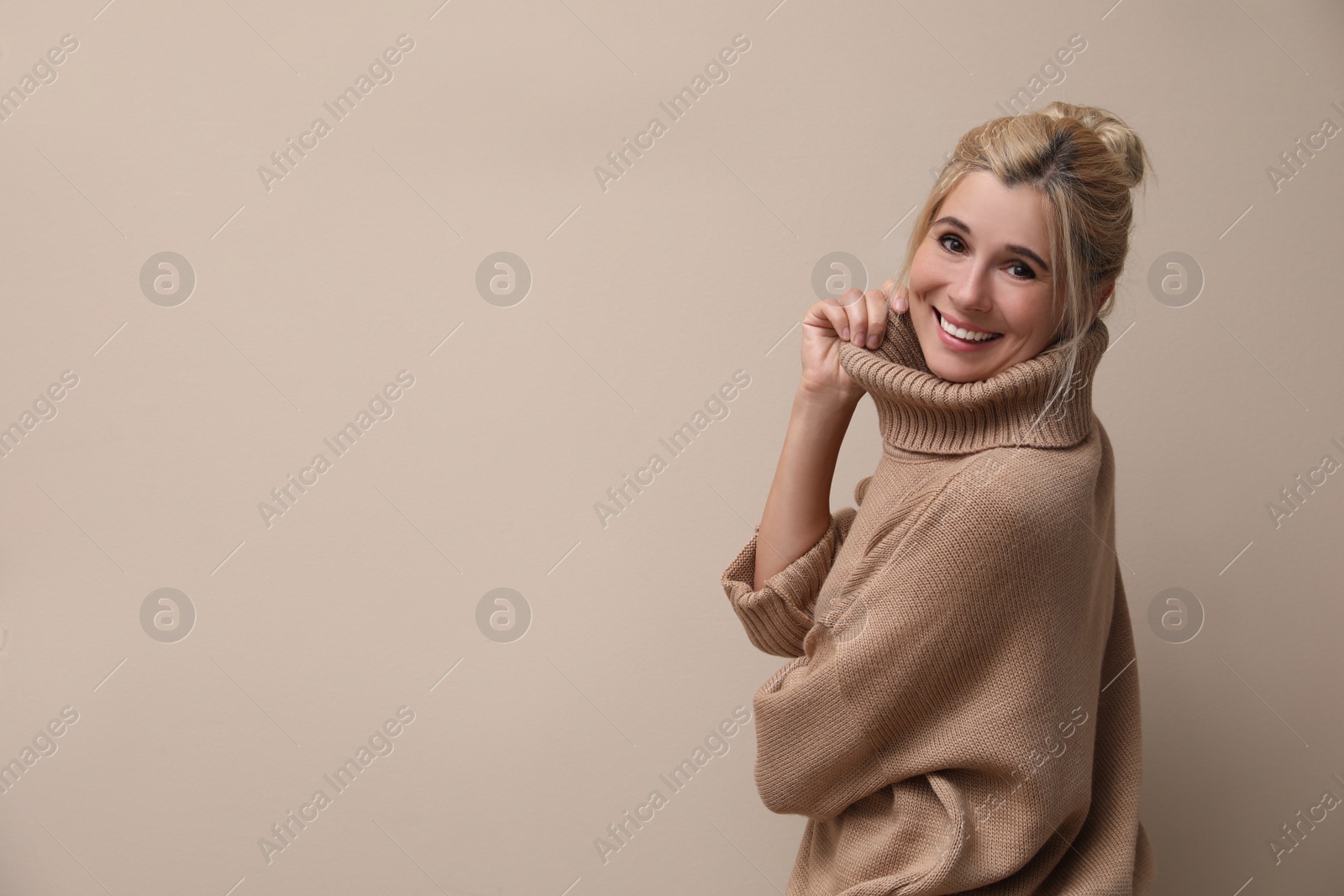 Photo of Happy woman in stylish sweater on beige background. Space for text